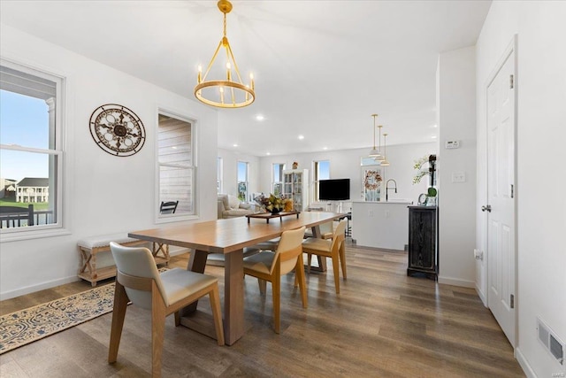 dining area featuring a chandelier, visible vents, a healthy amount of sunlight, and wood finished floors
