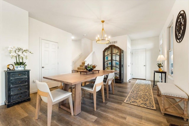 dining room featuring visible vents, wood finished floors, baseboards, stairway, and a chandelier