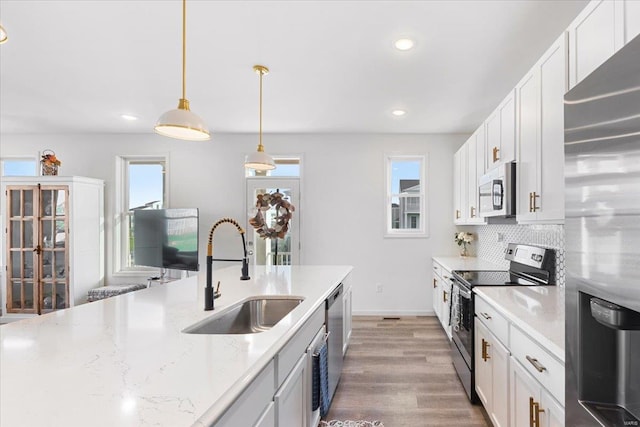 kitchen with decorative light fixtures, appliances with stainless steel finishes, a sink, white cabinets, and recessed lighting