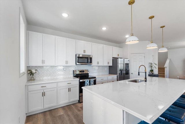 kitchen featuring stainless steel appliances, decorative backsplash, a sink, and dark wood-type flooring