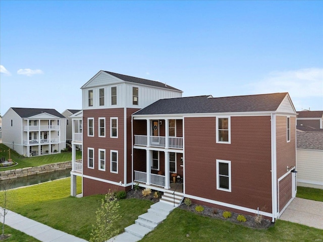 rear view of property featuring a lawn, a balcony, and a porch
