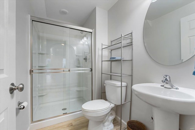 full bathroom with a sink, a stall shower, toilet, and wood finished floors