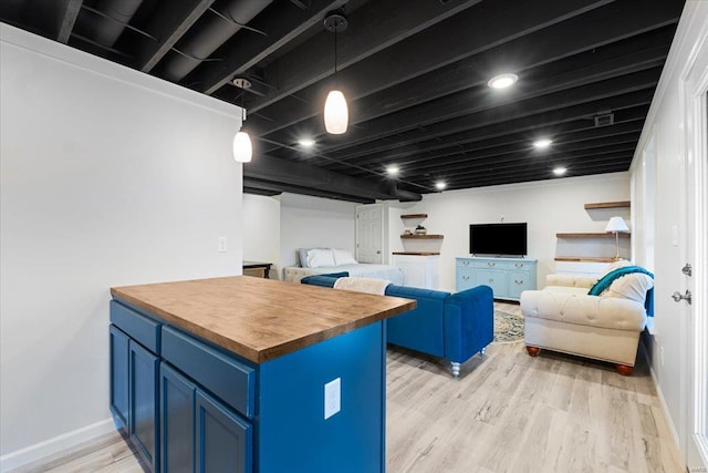 interior space with baseboards, light wood-style flooring, butcher block counters, and blue cabinetry
