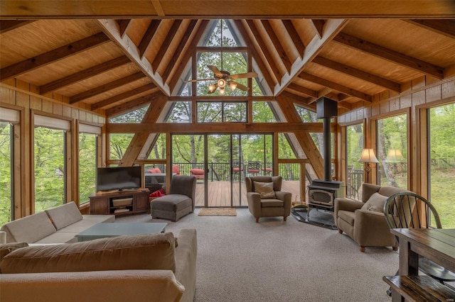 sunroom / solarium with beamed ceiling, a wood stove, high vaulted ceiling, and carpet floors