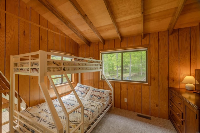 carpeted bedroom featuring wooden ceiling, wooden walls, lofted ceiling with beams, and visible vents