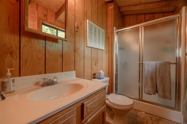 bathroom with a shower stall, wooden walls, vanity, and toilet