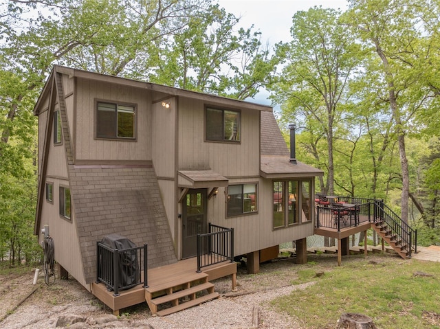 back of house featuring stairway, a deck, and a shingled roof