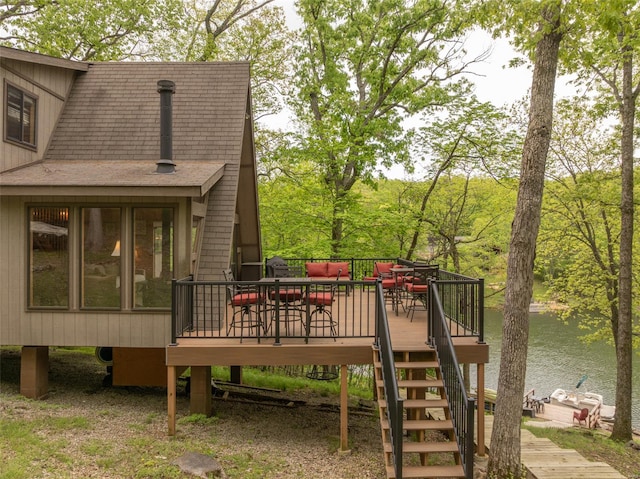 wooden terrace featuring a water view, an outdoor living space, and stairs