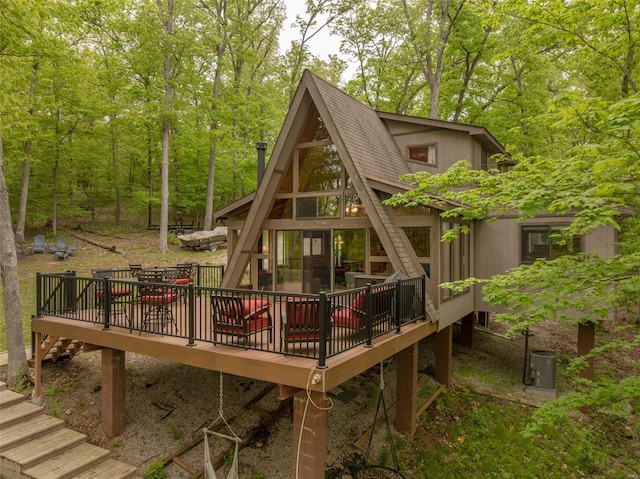 rear view of house featuring stairs, a deck, and a shingled roof
