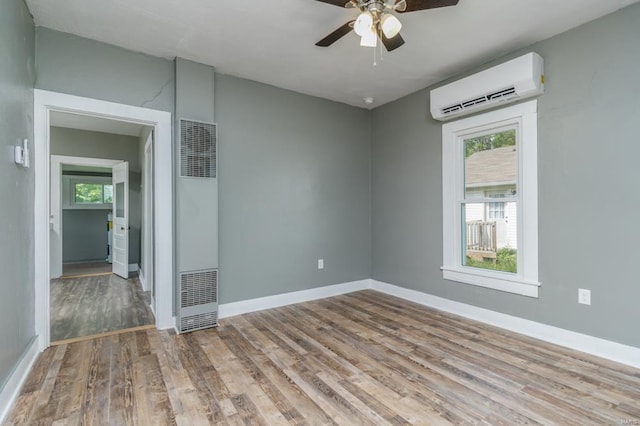 unfurnished room featuring an AC wall unit, a heating unit, wood finished floors, a ceiling fan, and baseboards
