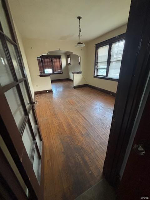 unfurnished dining area featuring baseboards and dark wood-type flooring
