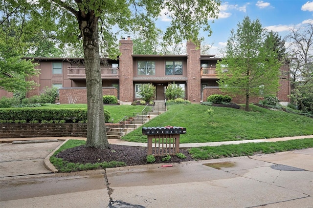 exterior space with brick siding, a front lawn, a balcony, and a chimney