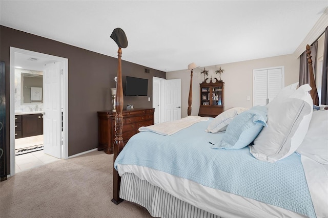 bedroom featuring baseboards, ensuite bathroom, a closet, and light colored carpet