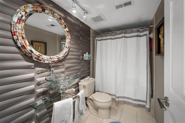 full bathroom with a textured ceiling, visible vents, tile patterned flooring, a sink, and toilet