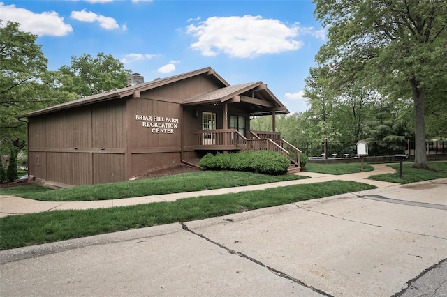view of front of house with a porch, a chimney, stairs, and a front lawn