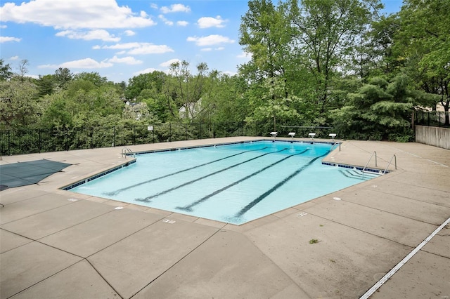 community pool with a patio and fence