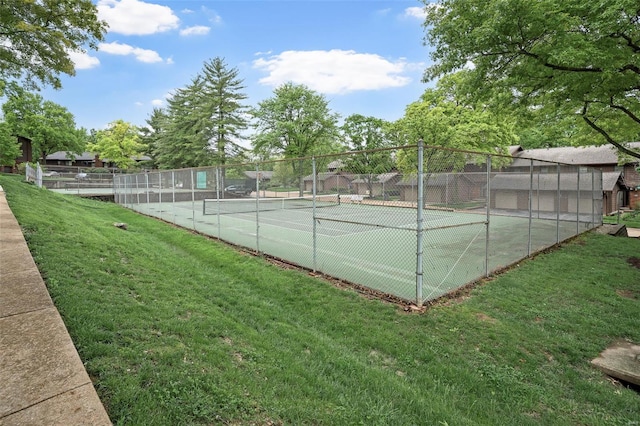 view of tennis court featuring a yard and fence