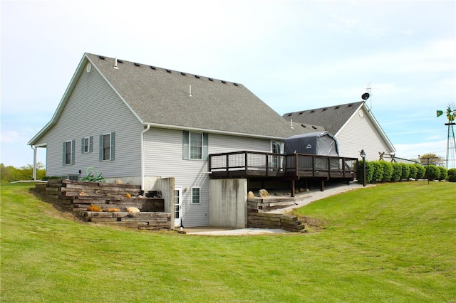 back of house featuring a lawn, a shingled roof, and a deck