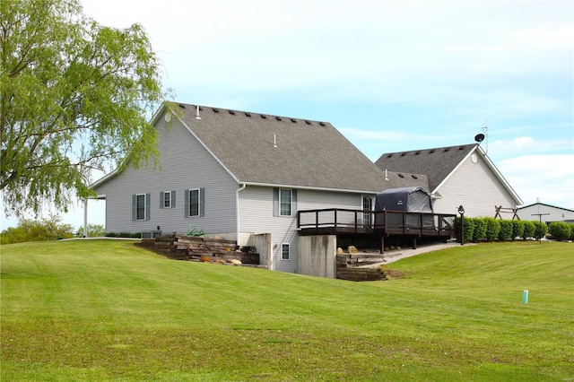 rear view of property featuring a yard, a wooden deck, and a shingled roof