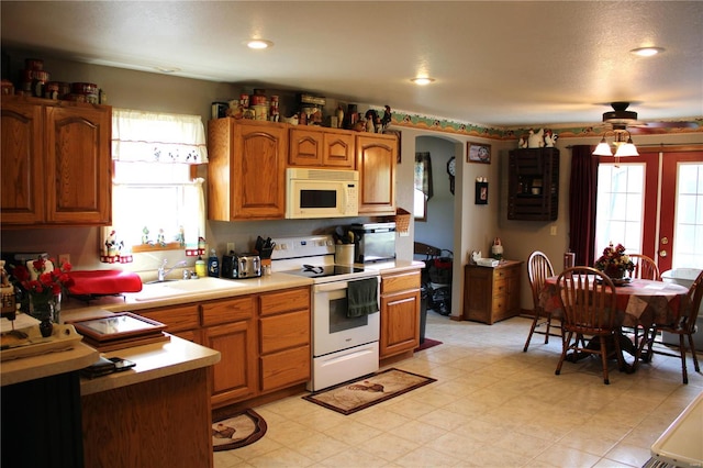 kitchen with light countertops, a ceiling fan, white appliances, and a healthy amount of sunlight