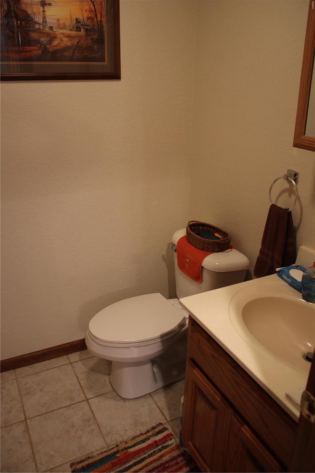half bathroom featuring vanity, tile patterned flooring, baseboards, and toilet