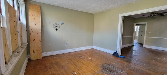 spare room featuring wood-type flooring, a ceiling fan, a textured ceiling, and baseboards