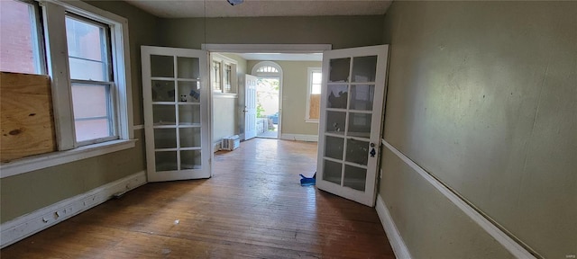 hallway featuring baseboards, french doors, and hardwood / wood-style flooring