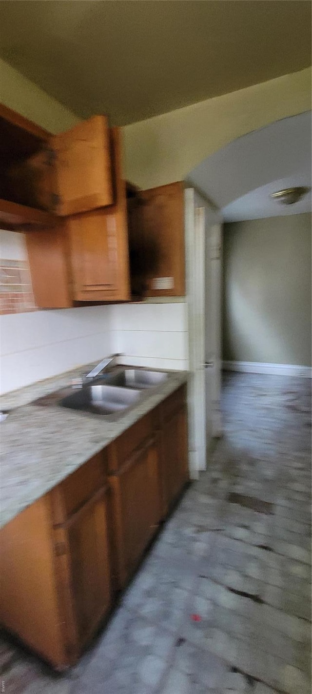 interior space featuring brown cabinetry, a sink, and baseboards