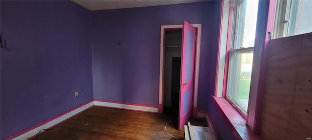 unfurnished room featuring baseboards, wood finished floors, and a wealth of natural light
