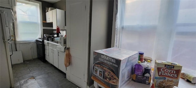 kitchen featuring gas stove, light countertops, and white cabinetry