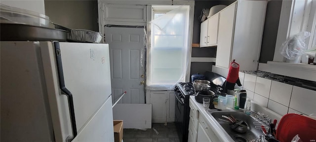 kitchen with black gas stove, freestanding refrigerator, white cabinets, and a wealth of natural light