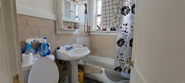 bathroom with toilet, tile walls, and shower / tub combo