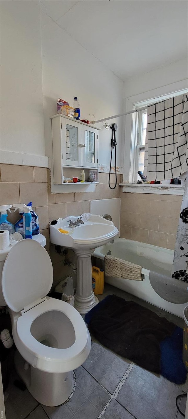 bathroom featuring toilet, tile patterned floors, tile walls, and a wainscoted wall