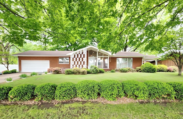 view of front of property with an attached garage, concrete driveway, a front lawn, and brick siding