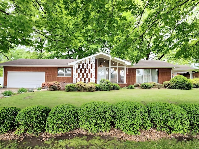 view of front of house featuring an attached garage, concrete driveway, a front lawn, and brick siding