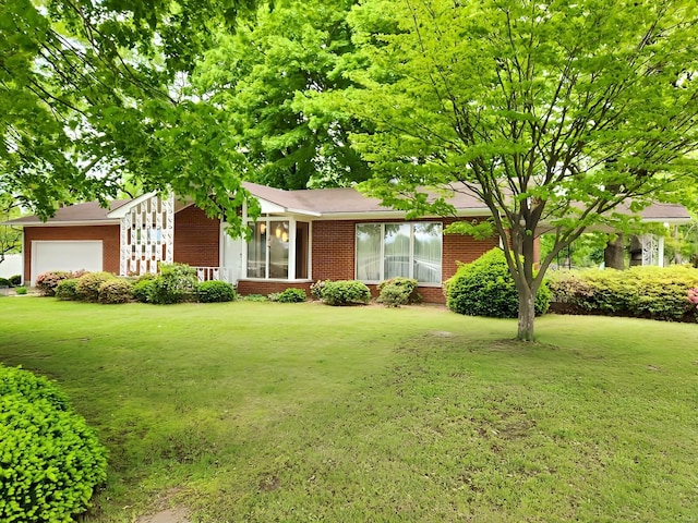 view of front of house with brick siding, a garage, and a front lawn