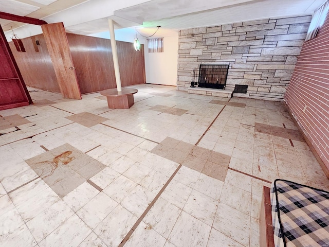 finished basement with tile patterned floors, wood walls, and a stone fireplace