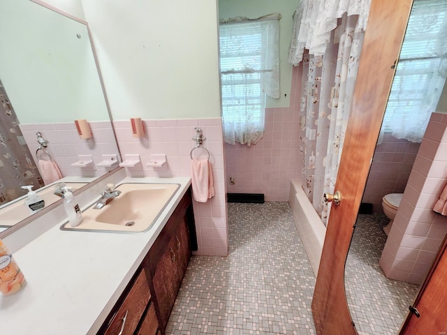 full bathroom featuring vanity, tile walls, wainscoting, and toilet