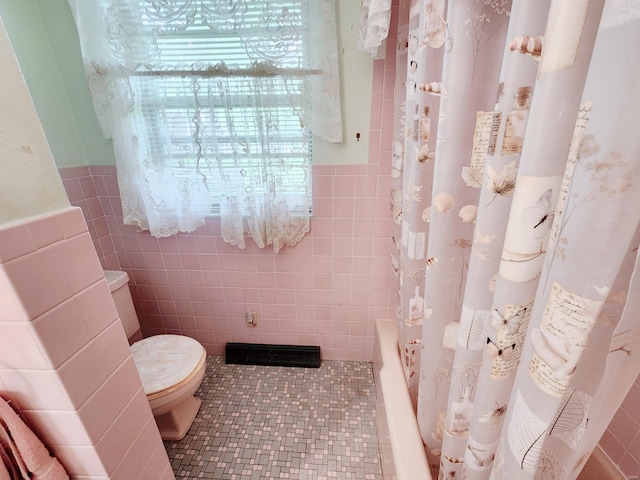 full bathroom featuring wainscoting, toilet, and tile walls