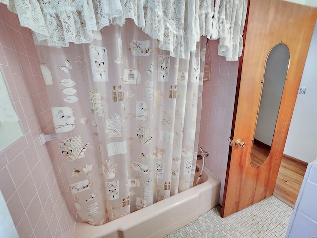 full bathroom with tile walls, shower / bathtub combination with curtain, and tile patterned flooring