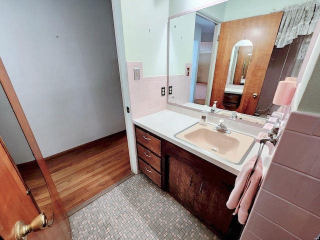 bathroom featuring vanity, wood finished floors, and tile walls