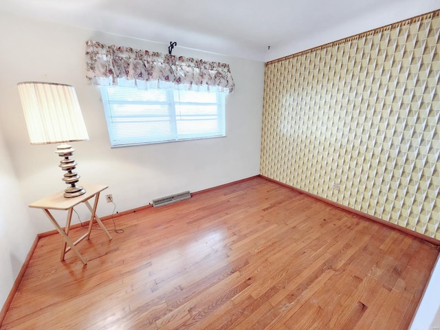 empty room with baseboards, light wood-type flooring, and visible vents