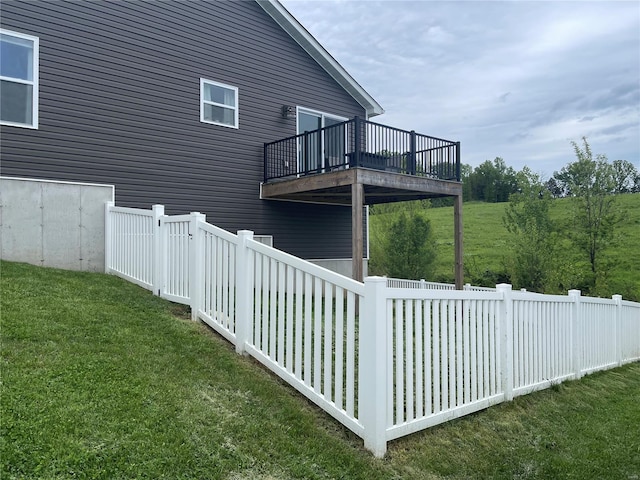 exterior space with fence, a wooden deck, and a lawn