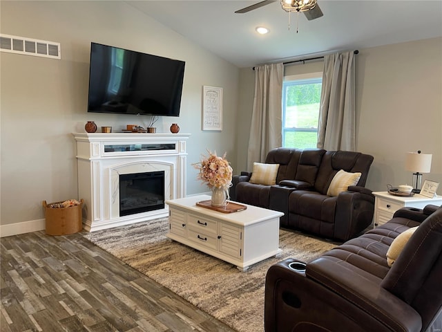 living room featuring lofted ceiling, wood finished floors, visible vents, a ceiling fan, and a glass covered fireplace