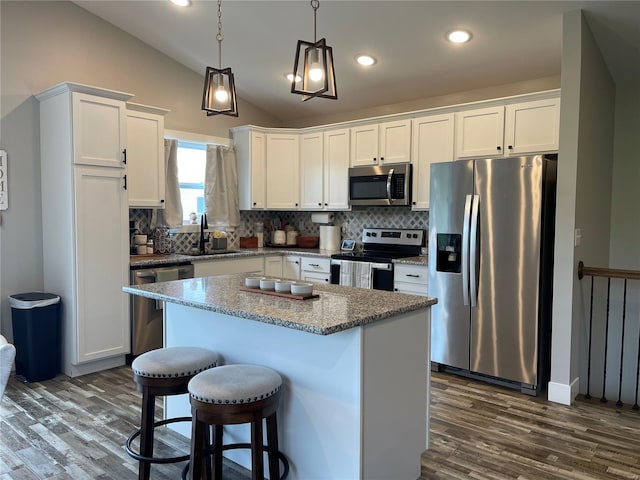 kitchen with a sink, stainless steel appliances, white cabinets, dark wood finished floors, and vaulted ceiling