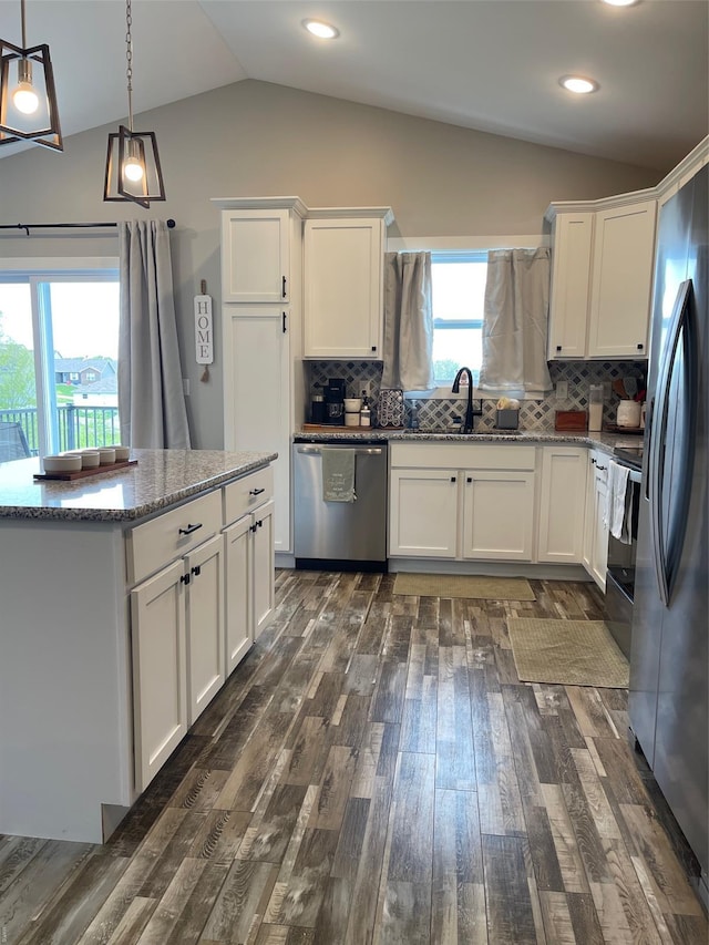 kitchen with a sink, stainless steel appliances, white cabinetry, lofted ceiling, and dark wood-style floors