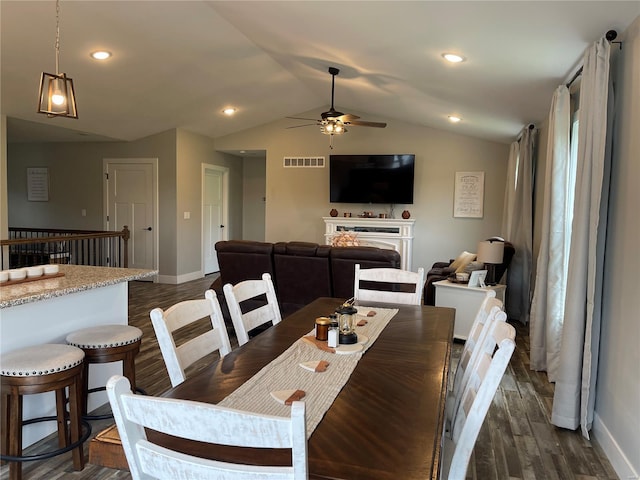 dining room featuring visible vents, vaulted ceiling, ceiling fan, dark wood-style flooring, and baseboards