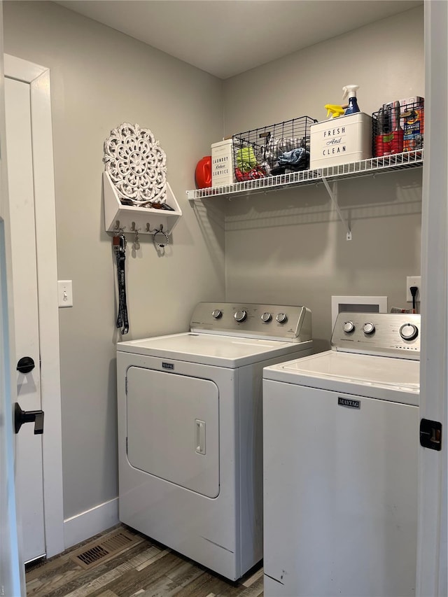 clothes washing area with laundry area, baseboards, wood finished floors, and washing machine and dryer