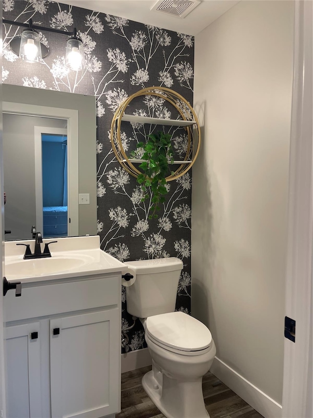 bathroom featuring visible vents, baseboards, wallpapered walls, and wood finished floors