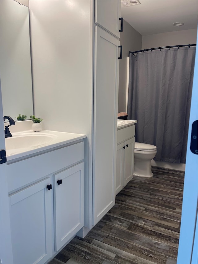 full bath with toilet, visible vents, wood finished floors, and vanity
